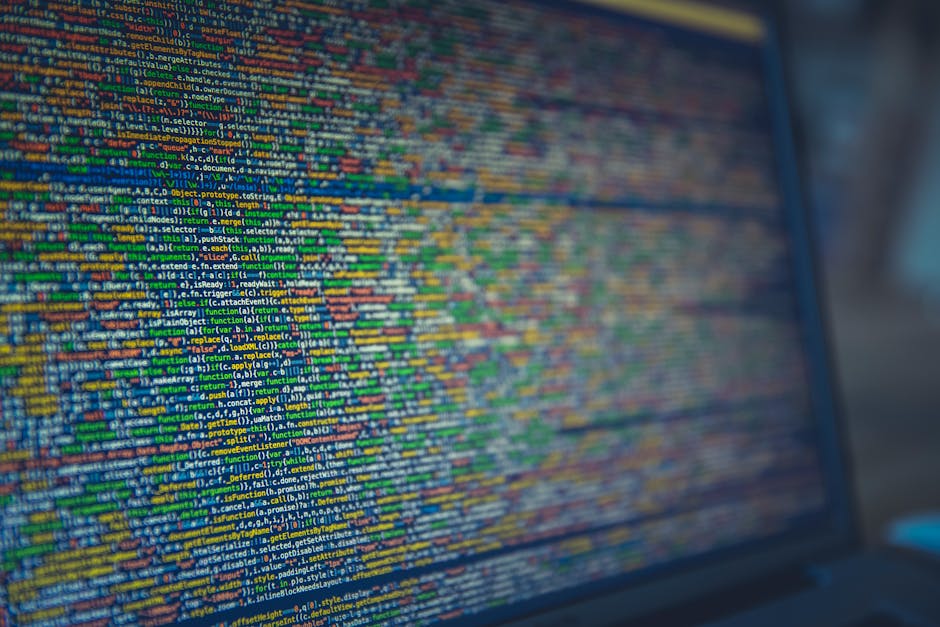 A close-up view of a computer screen displaying colorful lines of code in various programming languages, with text in green, yellow, blue, and red against a dark background. The code includes function